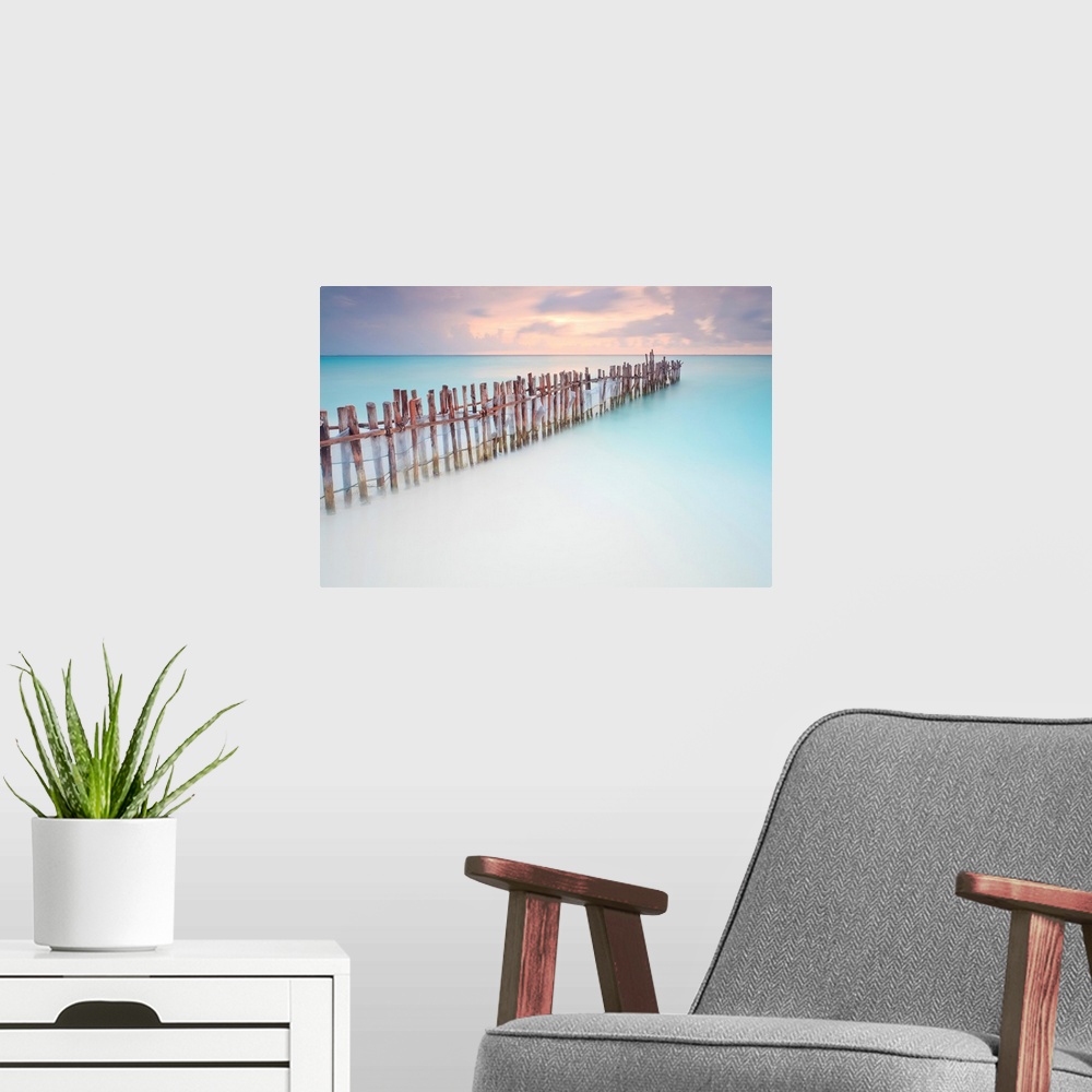 A modern room featuring Tranquil scene of Wooden posts in Caribbean sea, at sunset right after storm.