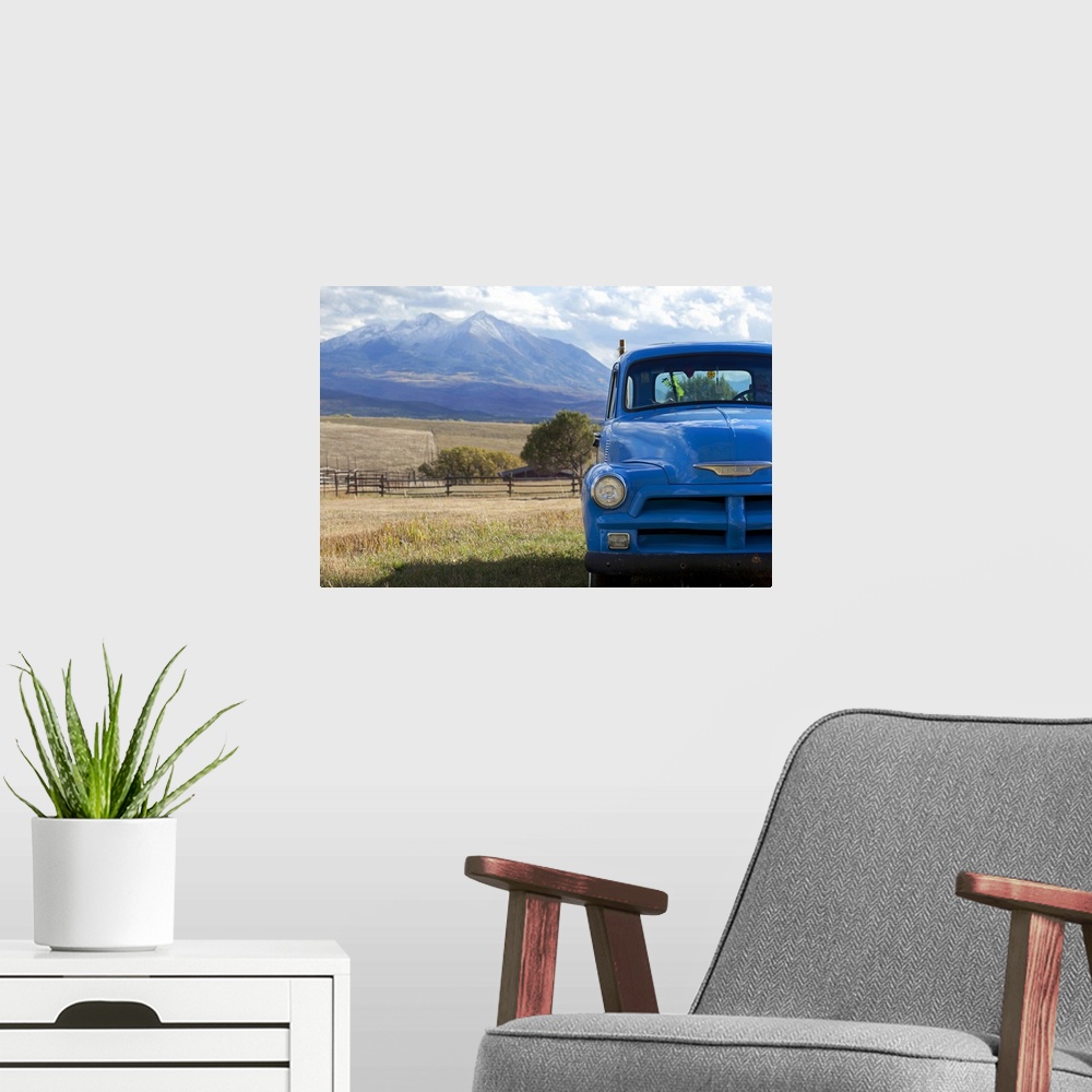 A modern room featuring Landscape, large photograph of part of the front of a blue, vintage truck, parked in a grassy fie...