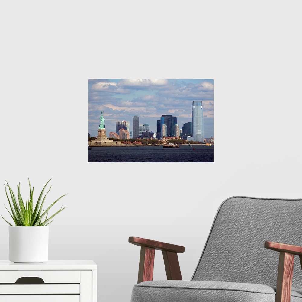 A modern room featuring The Statue of Liberty and the NYC skyline are photographed under a cloudy sky.