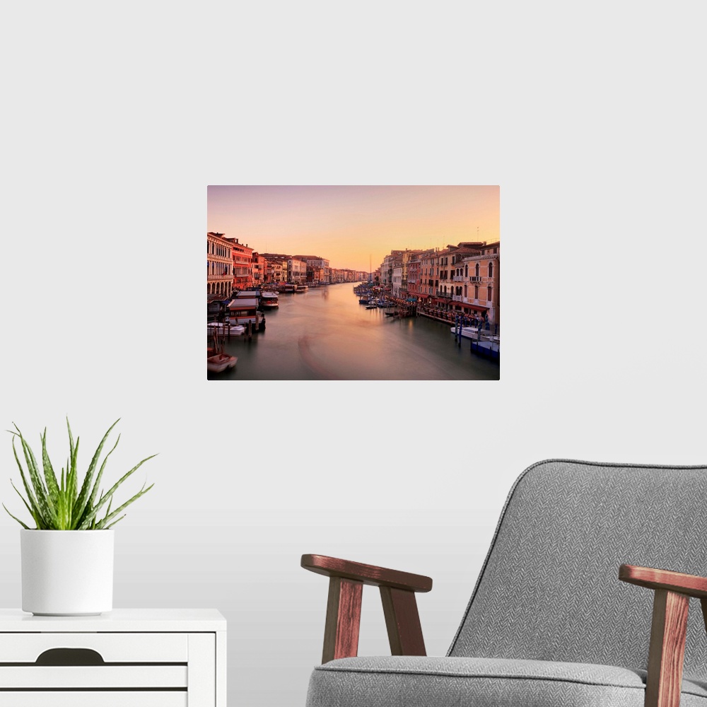 A modern room featuring Venetian canal side palaces around Rialto Bridge glow in last of evening light.