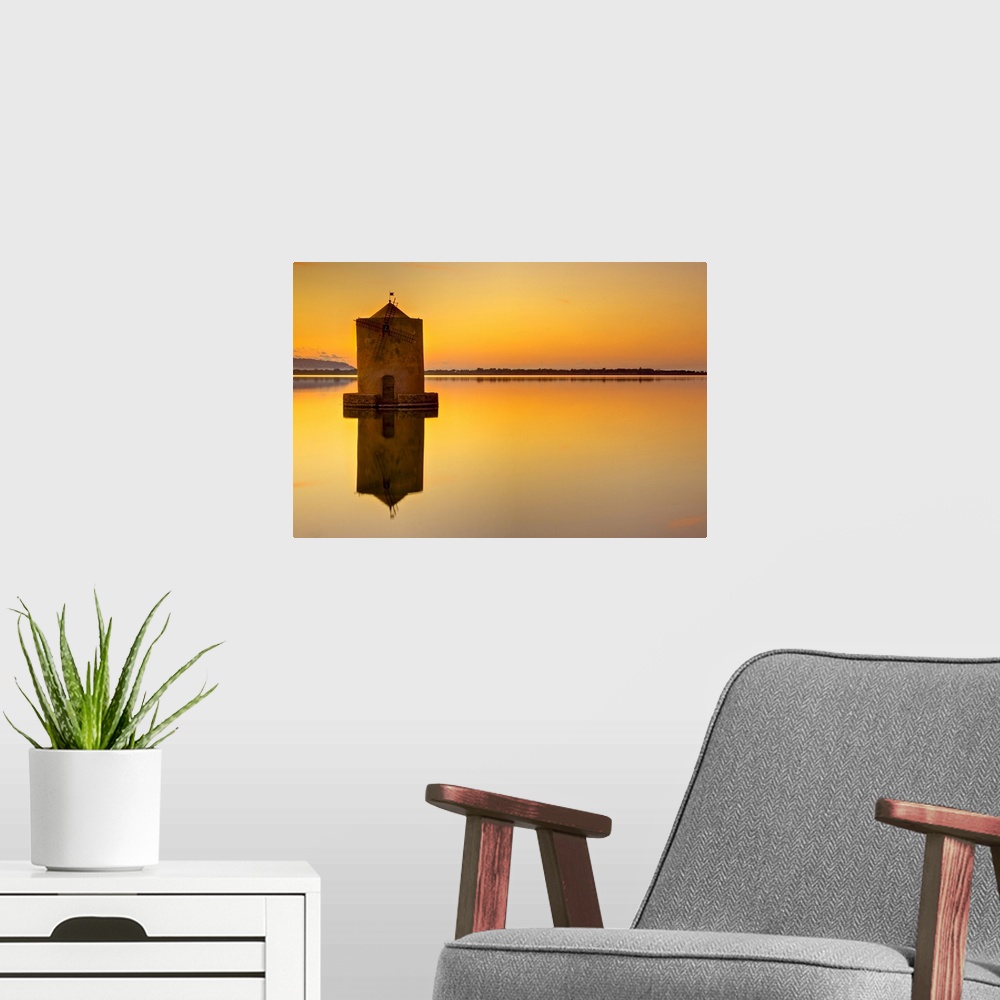 A modern room featuring Windmill at sunset in middle of water and reflection in water.