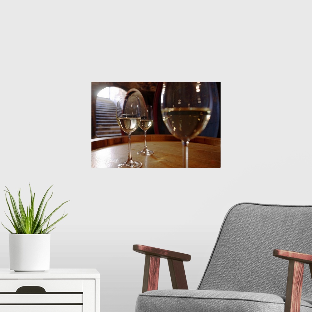 A modern room featuring Landscape, close up, large photograph of three glasses of white wine sitting on a wooden surface,...