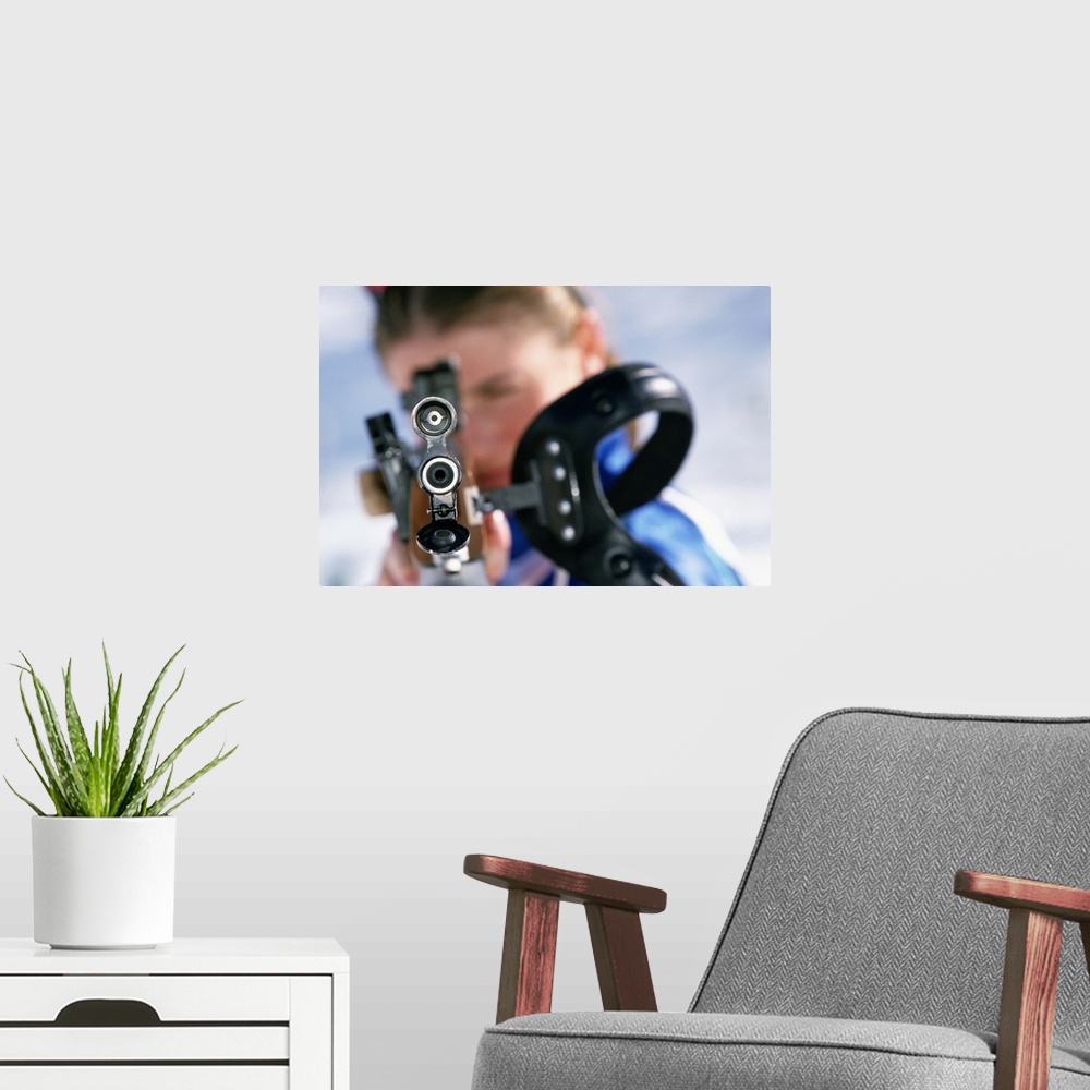 A modern room featuring Woman shooting rifle in biathlon (focus on nozzle)