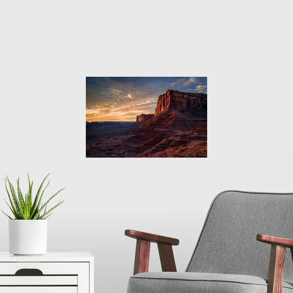 A modern room featuring The rising sun spreads warm light across the face of Monument Valley's Mitchell Mesa.
