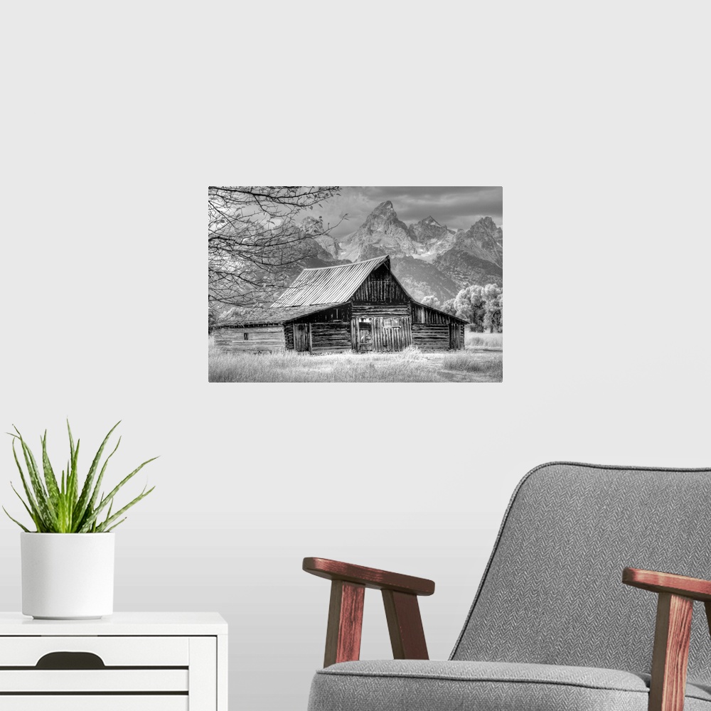 A modern room featuring Black and white photo of an old barn in a field with the Grand Teton mountain range in the distance.