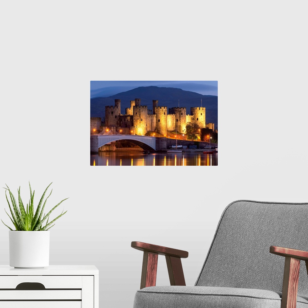 A modern room featuring Conwy Castle illuminated at night, Conwy, Wales. Spring (May) 2017.