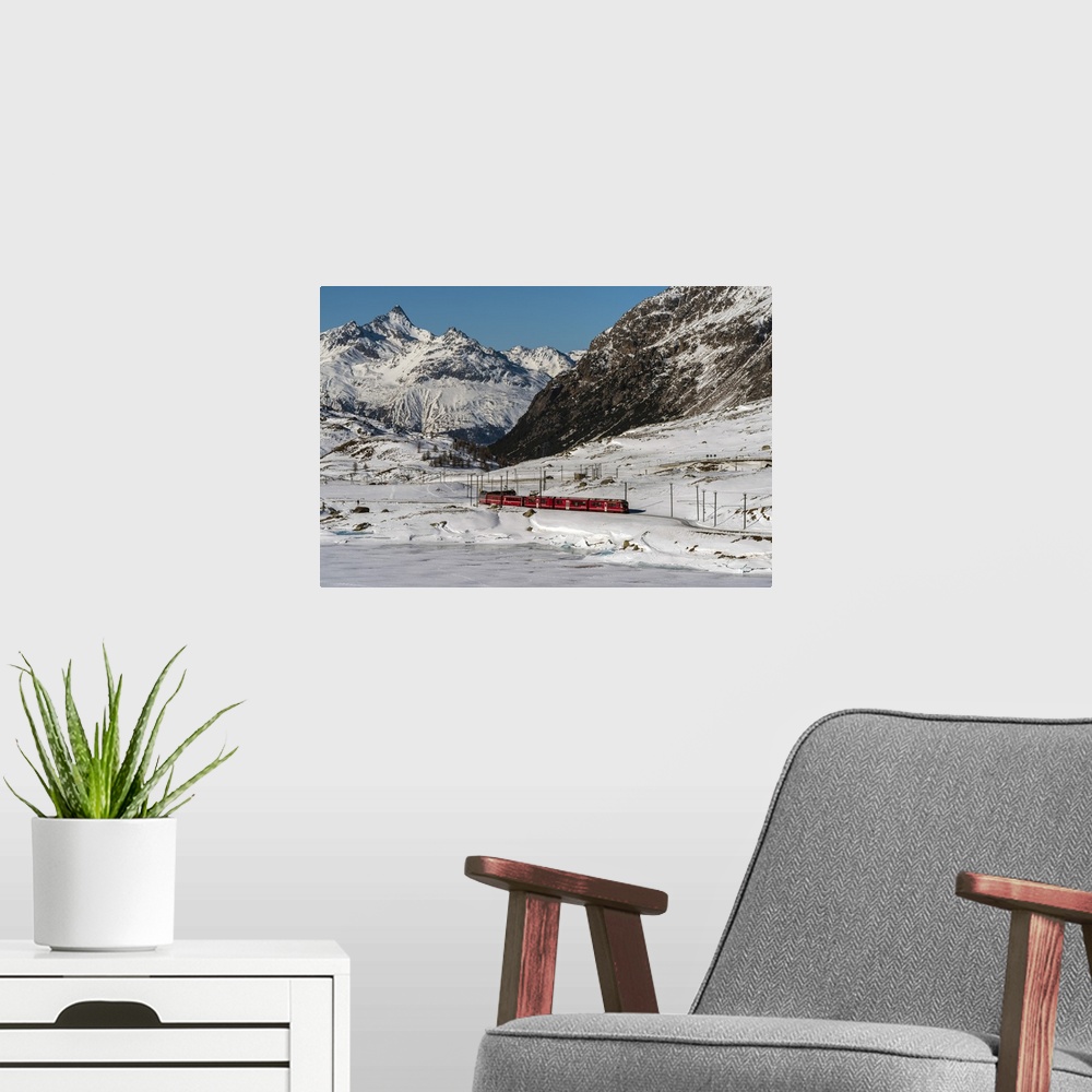 A modern room featuring The famous Bernina Express red train passing Lago Bianco in a scenic winter mountain landscape, G...