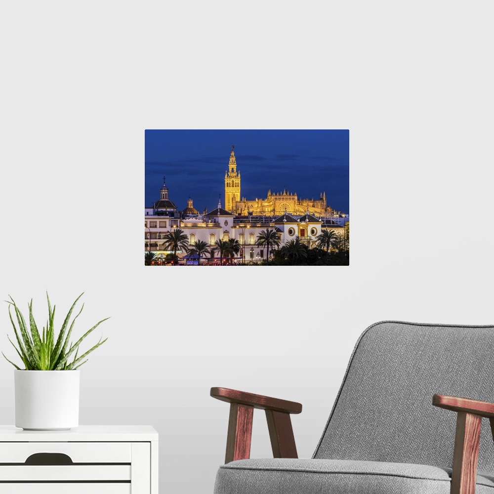 A modern room featuring Night view of city skyline with Cathedral and Giralda bell tower, Seville, Andalusia, Spain.