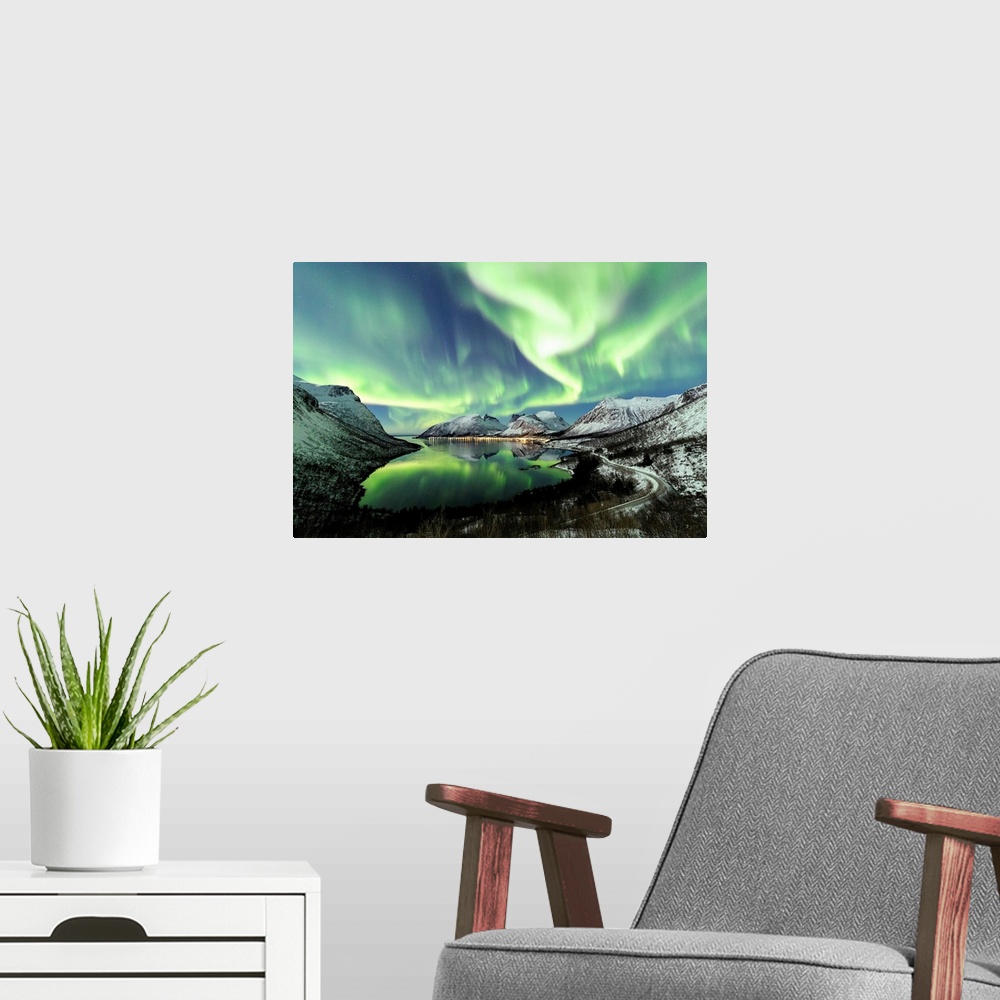 A modern room featuring Northern lights and stars light up the snowy peaks reflected in the cold sea Bergsbotn Senja Trom...
