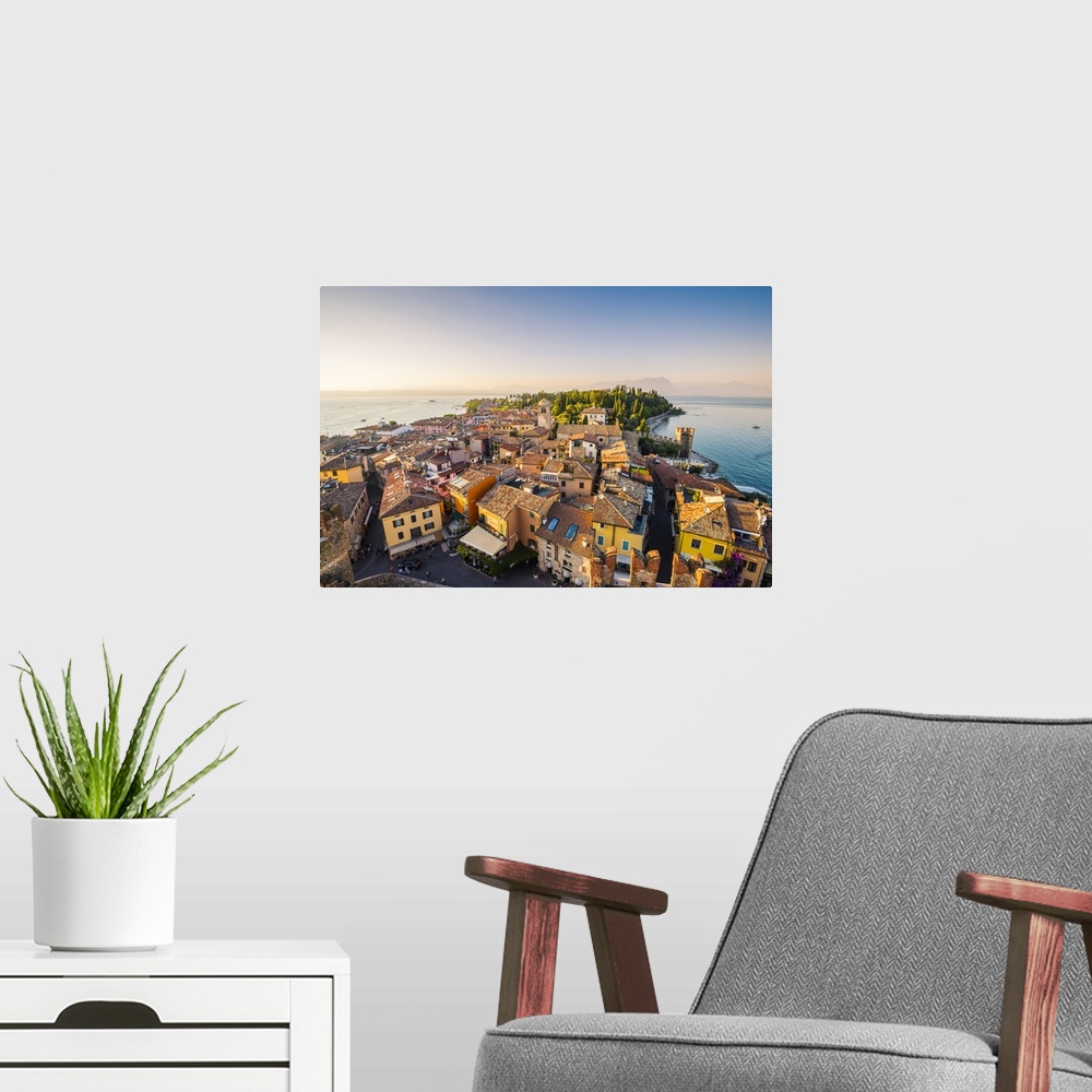 A modern room featuring Sirmione, lake Garda, Brescia province, Lombardy, Italy. High angle view of the old town at sunset.