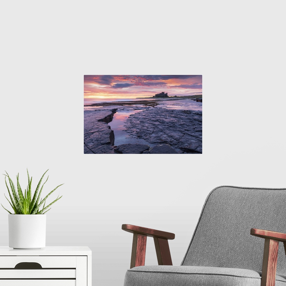 A modern room featuring Sunrise over Bamburgh Castle from the rocky shores of Bamburgh Beach, Northumberland, England. Au...