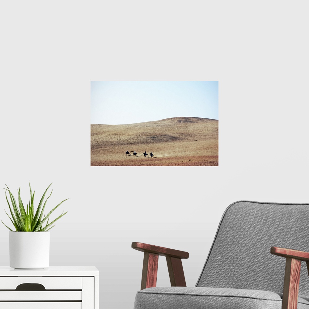 A modern room featuring Four young men riding their horses, bareback, through the desert near the Great Pyramids; Giza, E...