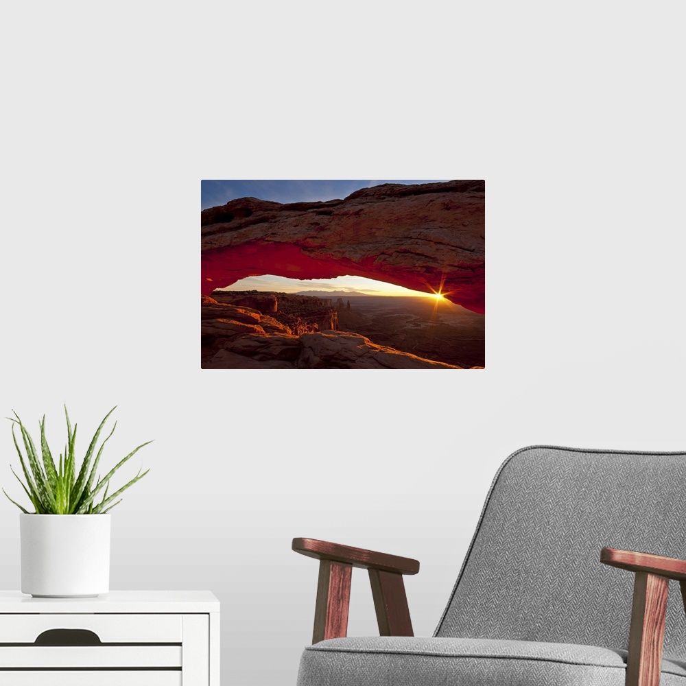 A modern room featuring A photograph is taken through the mesa arch as the sun begins to rise over the horizon.
