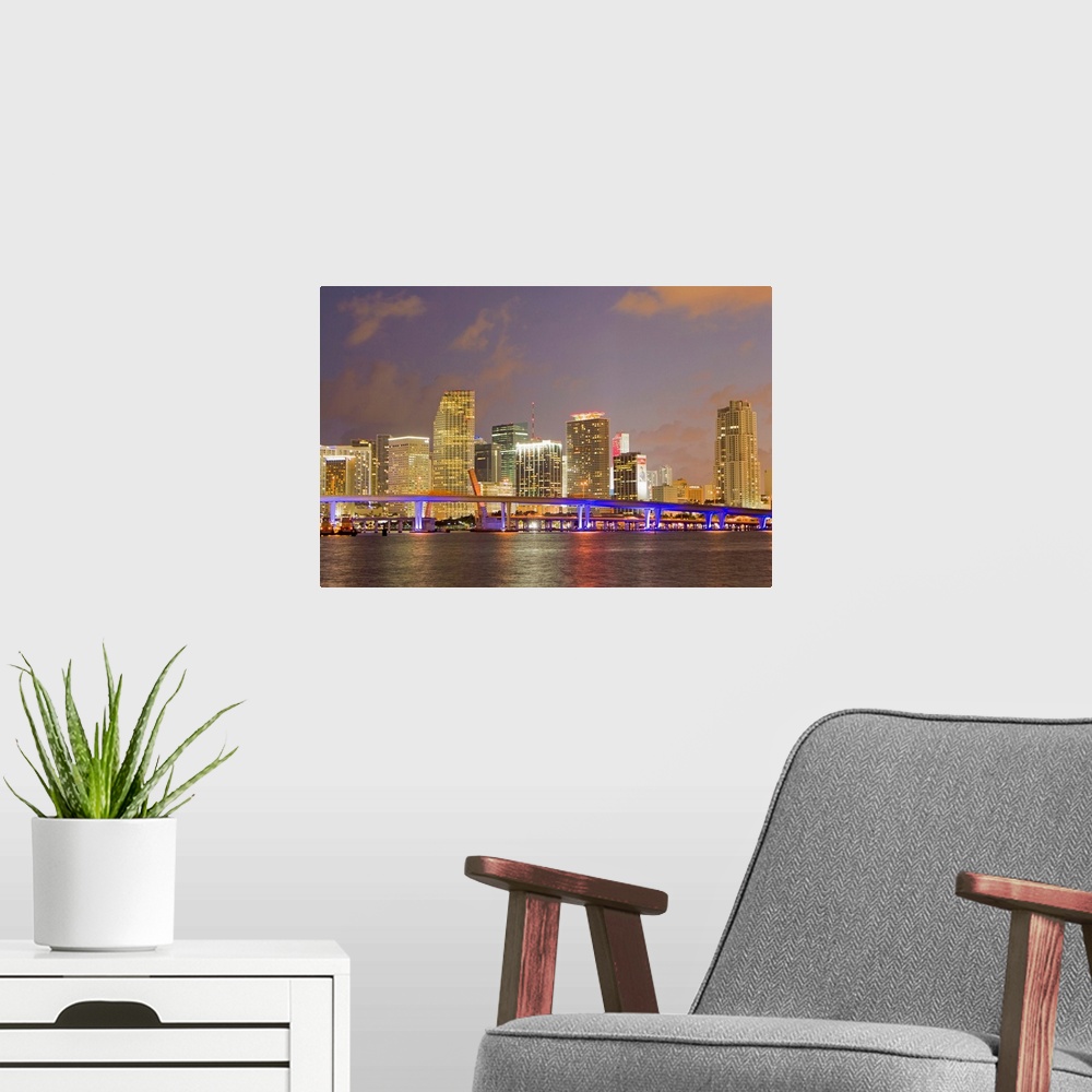A modern room featuring The Miami causeway and skyline at night.