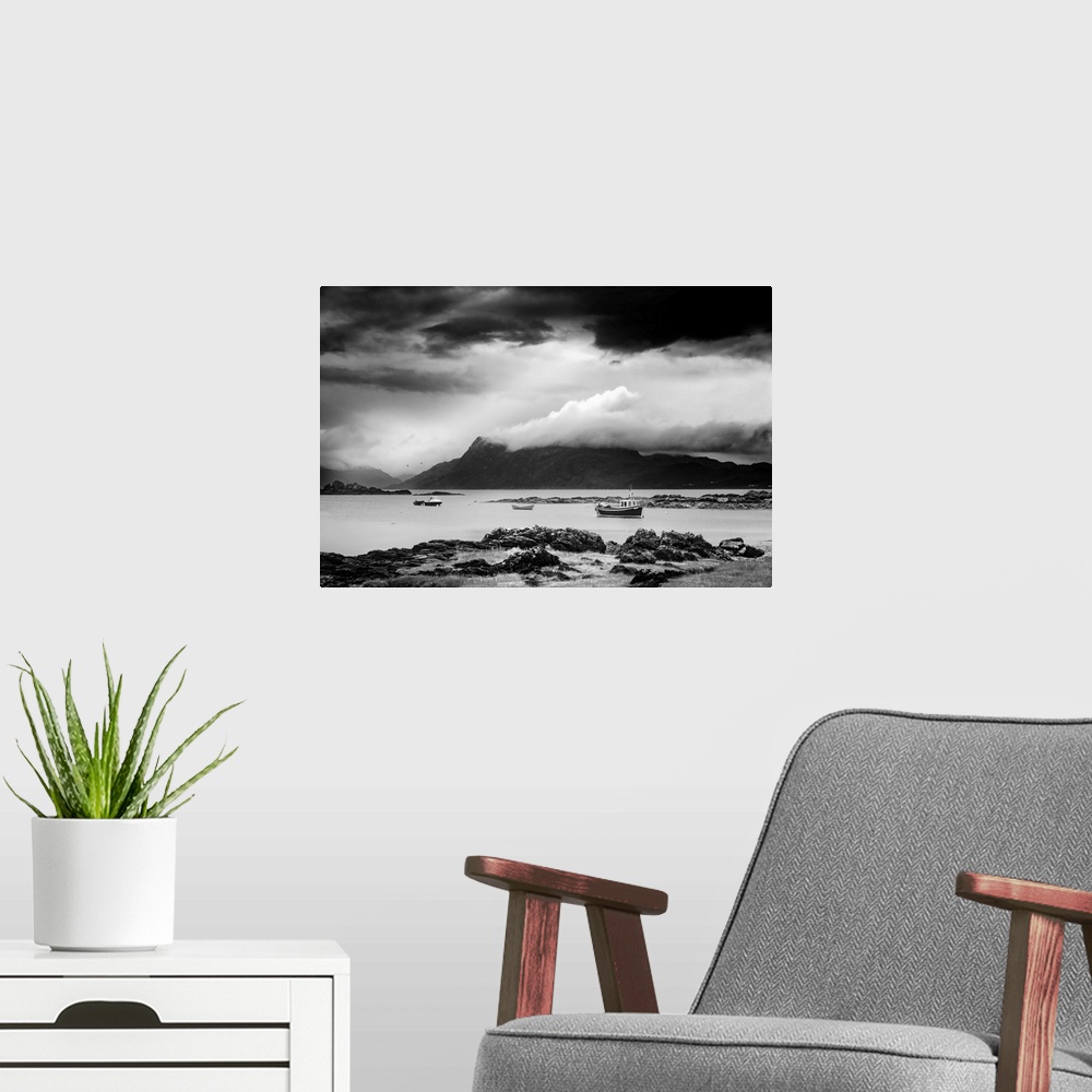 A modern room featuring Black and white landscape photograph of a cloudy sky over a mountainous lake with boats.