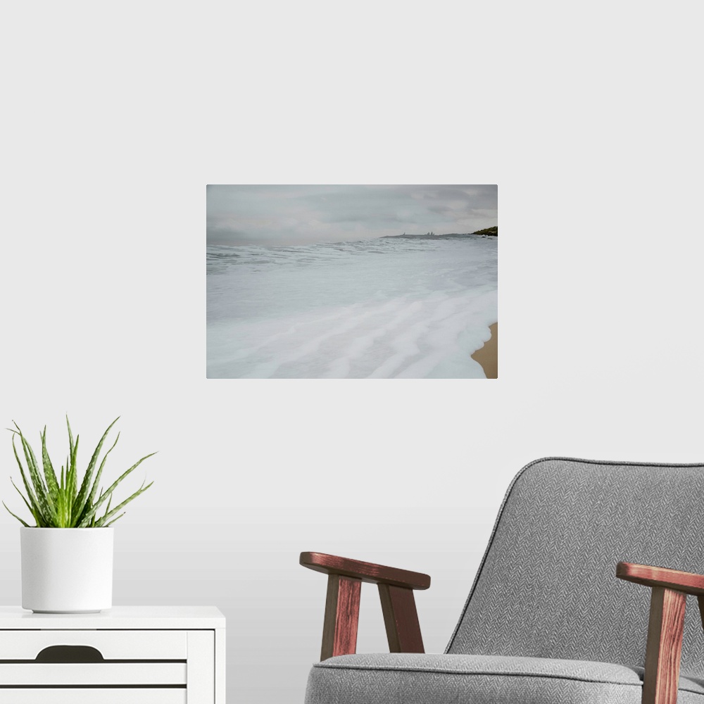 A modern room featuring Photograph of foamy sea water rushing up the sandy shore on a cold Winter's day.