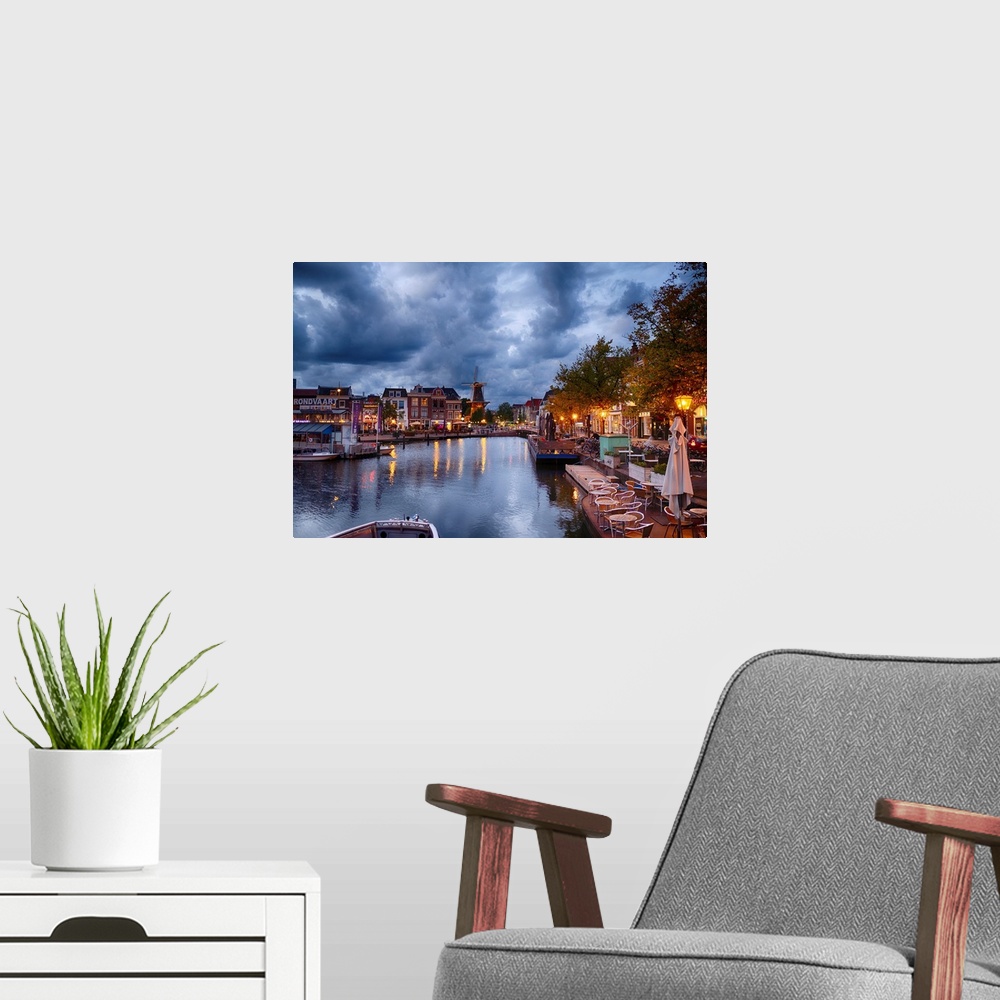 A modern room featuring Canal and windmill in Leiden at night, Netherlands.