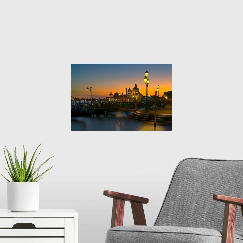 A modern room featuring Sunset over Venice, Italy with yellow lit lampposts and calm waters.