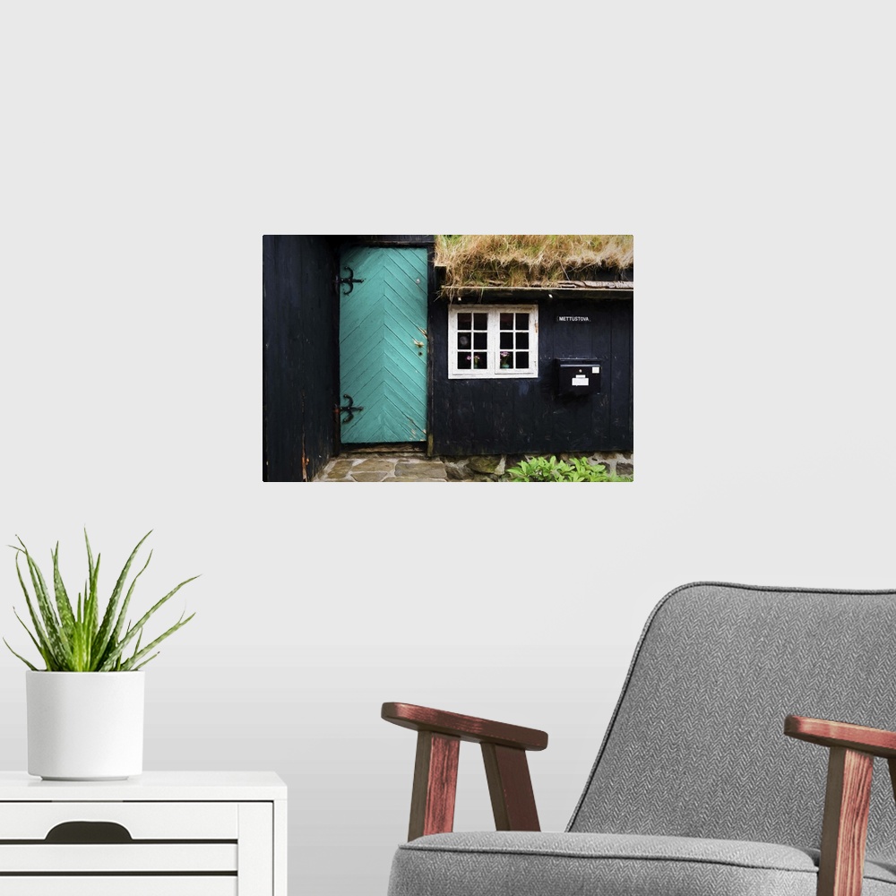 A modern room featuring The side of a black house with a turquoise door and white window frames.