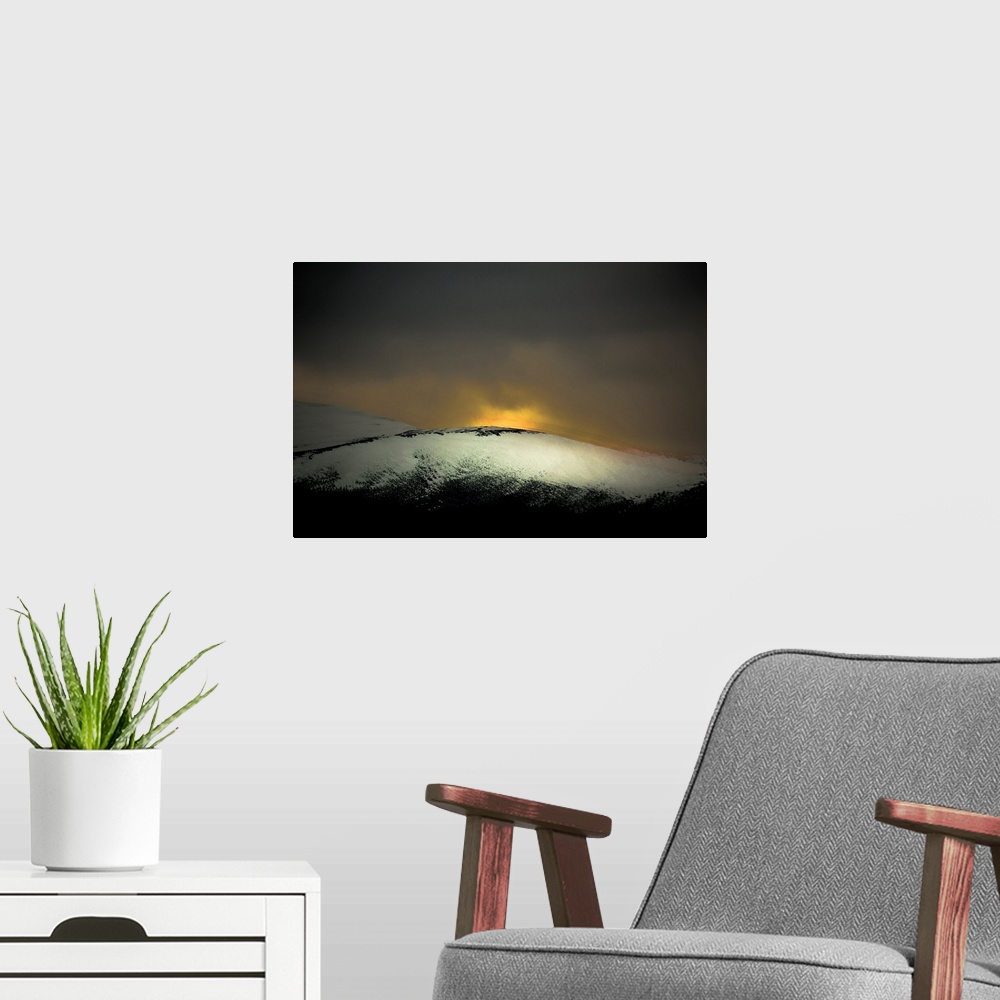 A modern room featuring A distressed photo a snow covered hill with dawn rising above it.