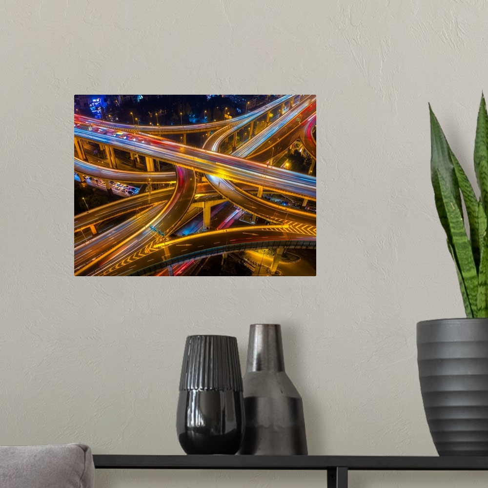 A modern room featuring Ariel view of highway bridges intertwining as cars drive by at night.