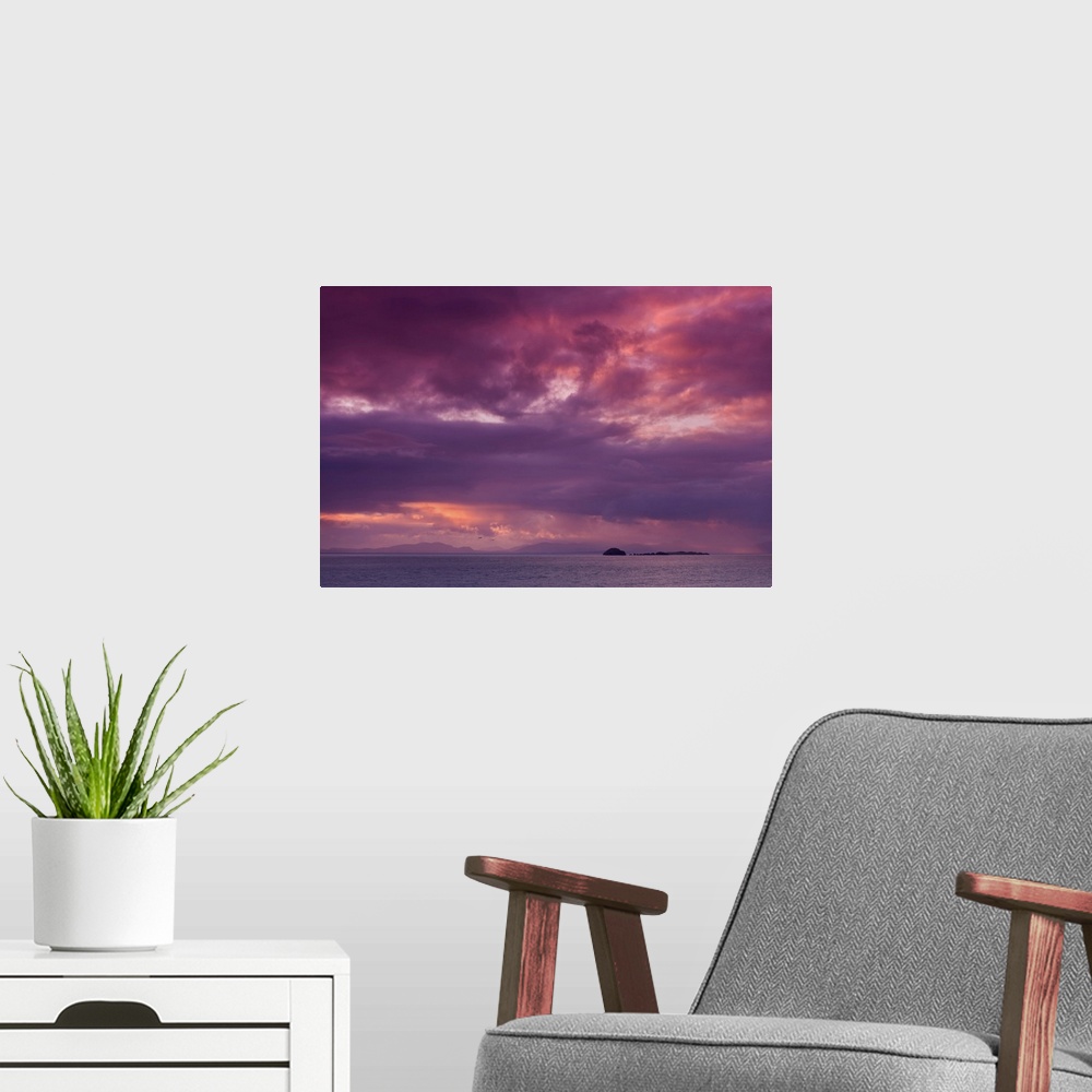 A modern room featuring Fine art photo of a dramatic skyscape over a calm ocean with a small island in the distance.