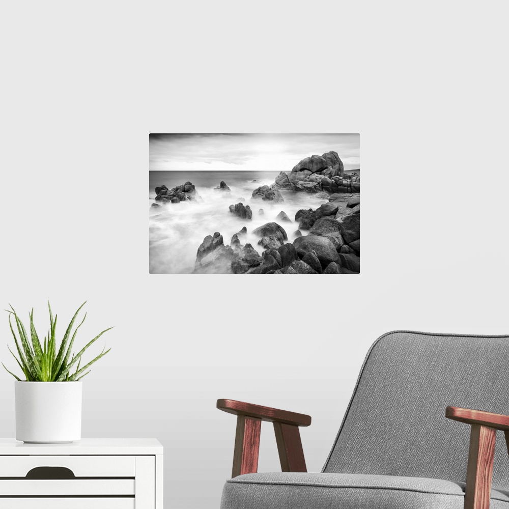 A modern room featuring A black and white photograph of a rocky coastline.