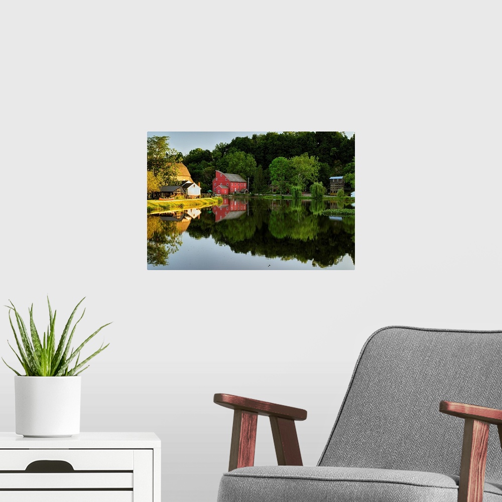 A modern room featuring Fine art photo of a bright red house at the edge of a calm lake, with the reflection of the fores...
