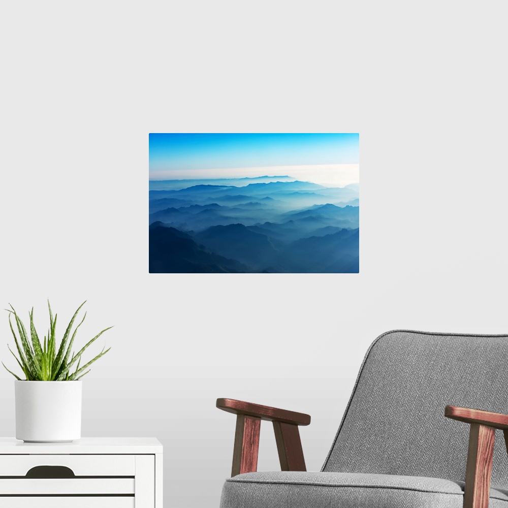 A modern room featuring Mountains of Laos seen from the sky in a bluish atmosphere at sunrise