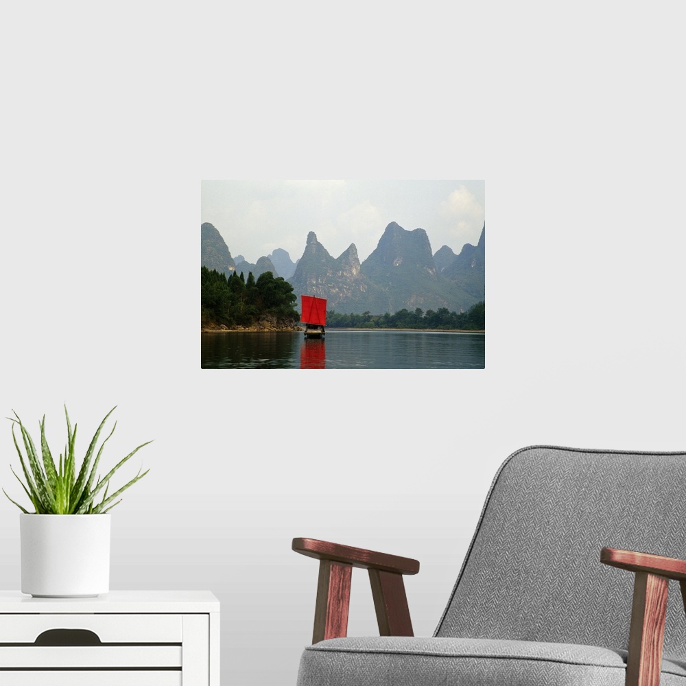 A modern room featuring A small boat in a Chinese river is photographed in front of immense cliffs.