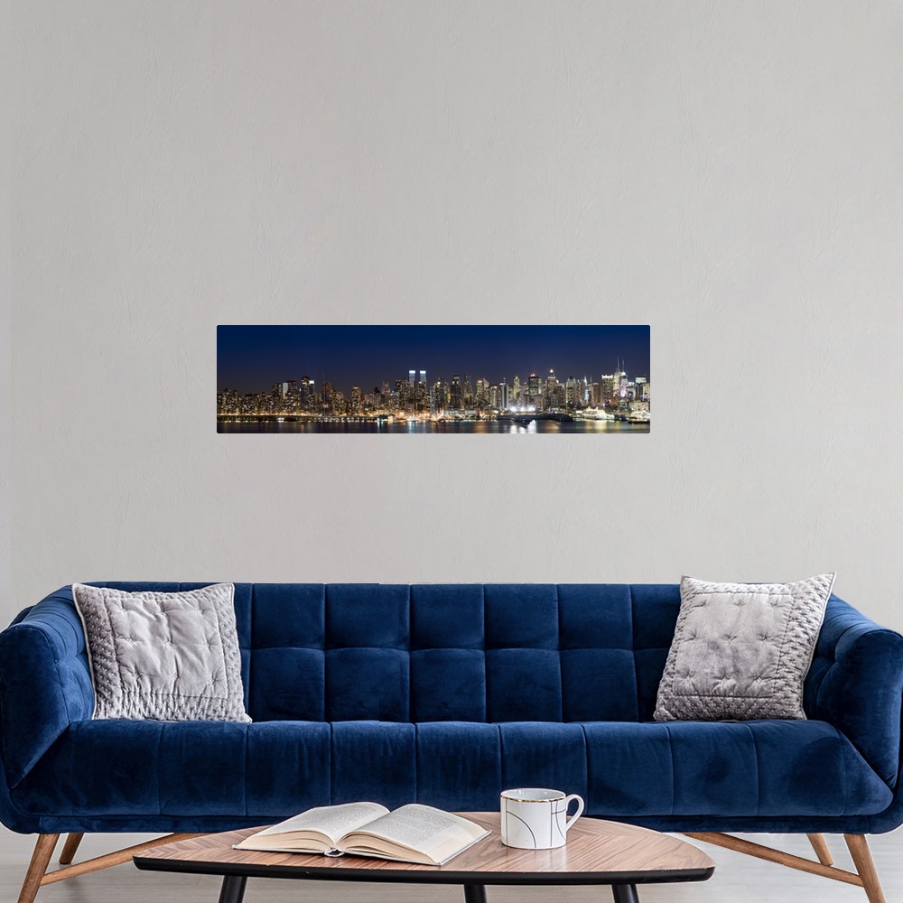 A modern room featuring This wall art is a panoramic photograph of the marvelous city skyline illuminated at night.