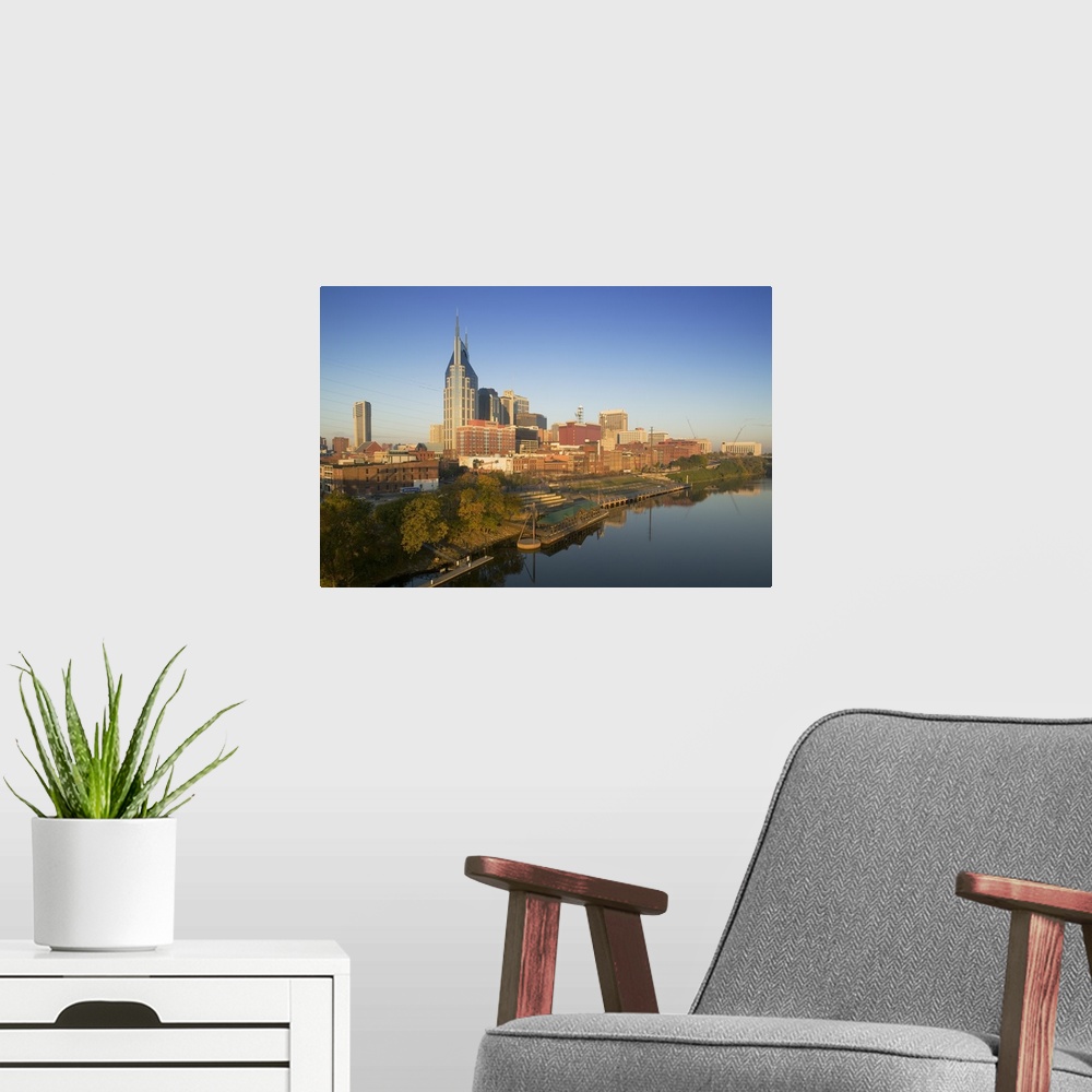 A modern room featuring This oversize piece is a photograph taken of the skyline in Nashville that sits along a body of w...