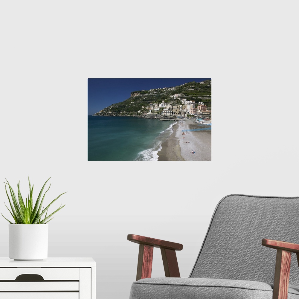 A modern room featuring A large cliff with buildings and homes built in it is photographed with the ocean water and beach...