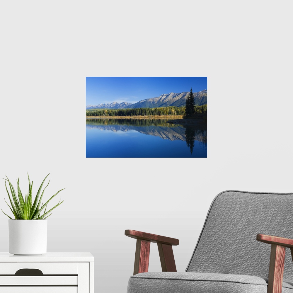 A modern room featuring Big canvas photo of mountains and their reflection onto the lake in front of them.