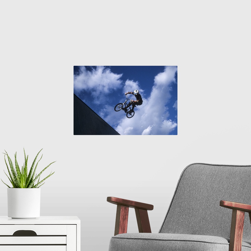 A modern room featuring Teenage boy flies over the vert on a BMX bike