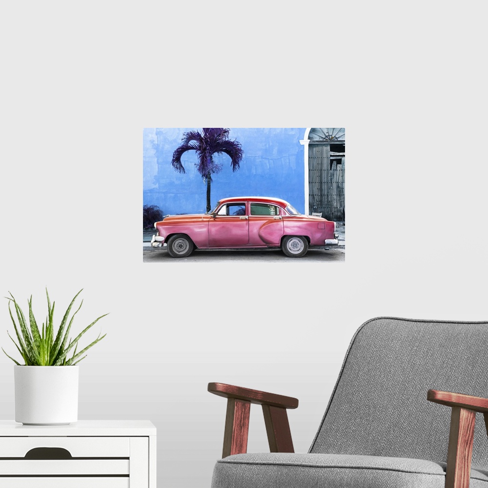 A modern room featuring Photograph of a pink vintage car parked outside of a blue building with a palm tree.