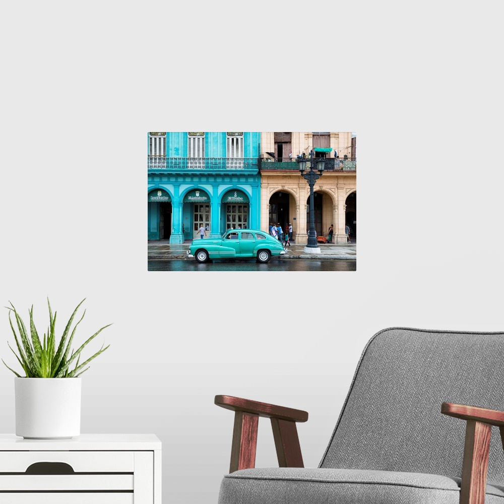 A modern room featuring Photograph of a turquoise vintage car parked outside of a bright blue building in downtown Havana.