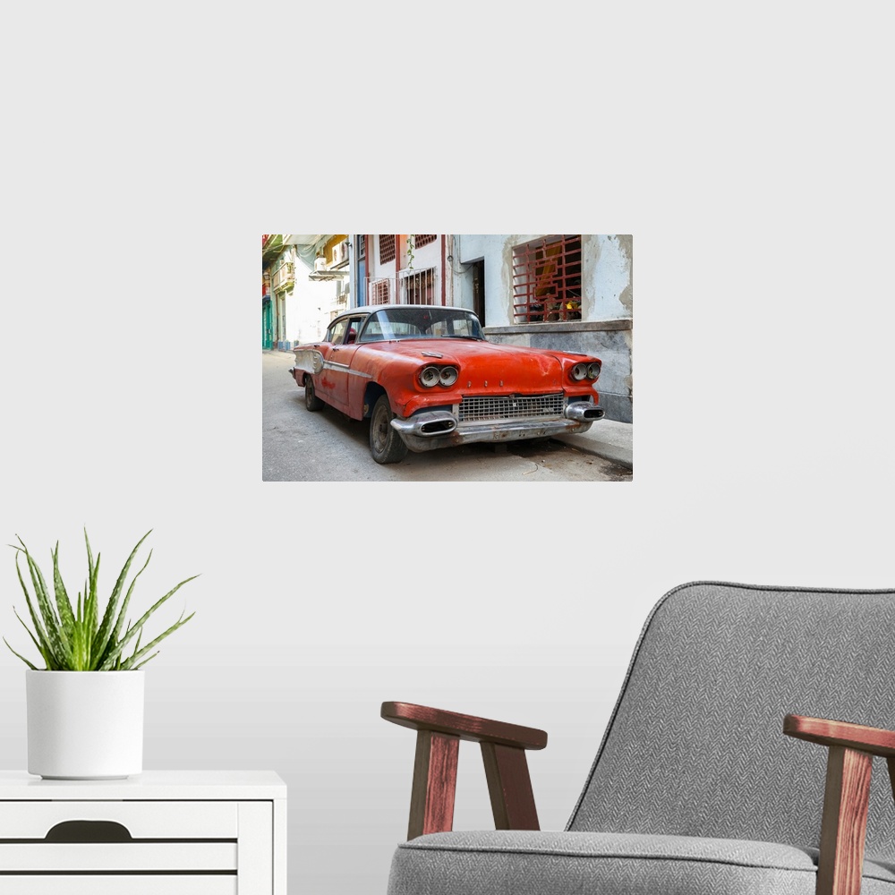A modern room featuring Photograph of an old beat up red car parked on the streets of Havana.