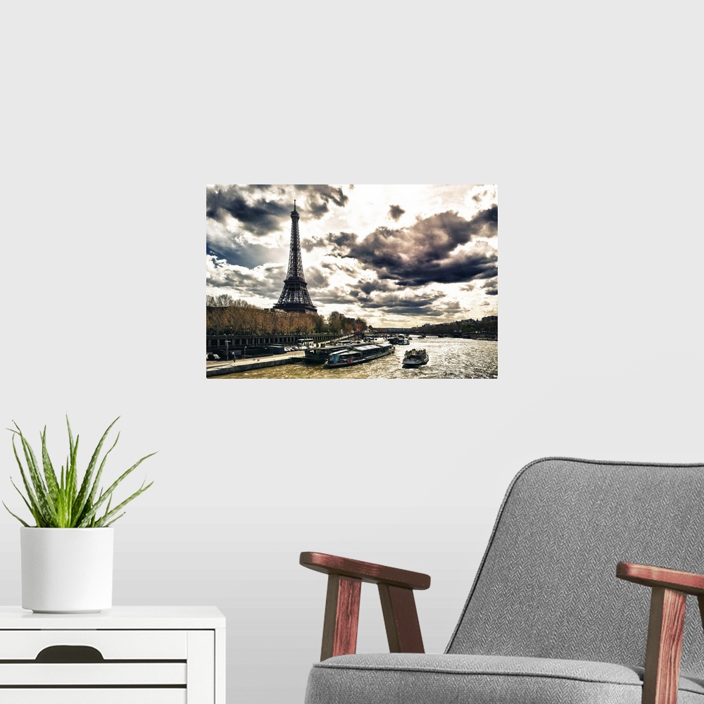 A modern room featuring Fine art photo of the Eiffel Tower on the edge of the Seine River with dramatic clouds.