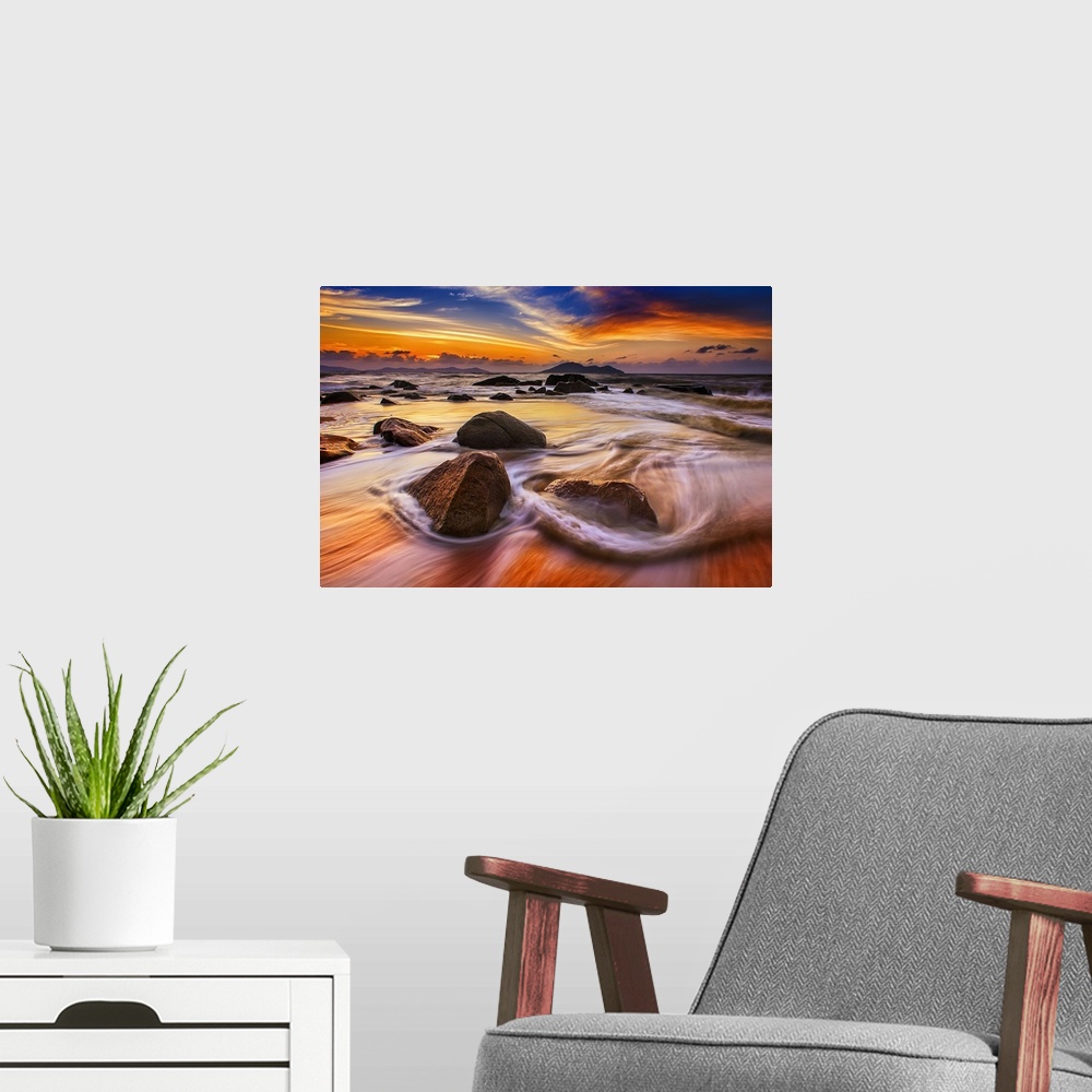 A modern room featuring Beautiful sunset over low tidewater rushing over rocks on the beach.