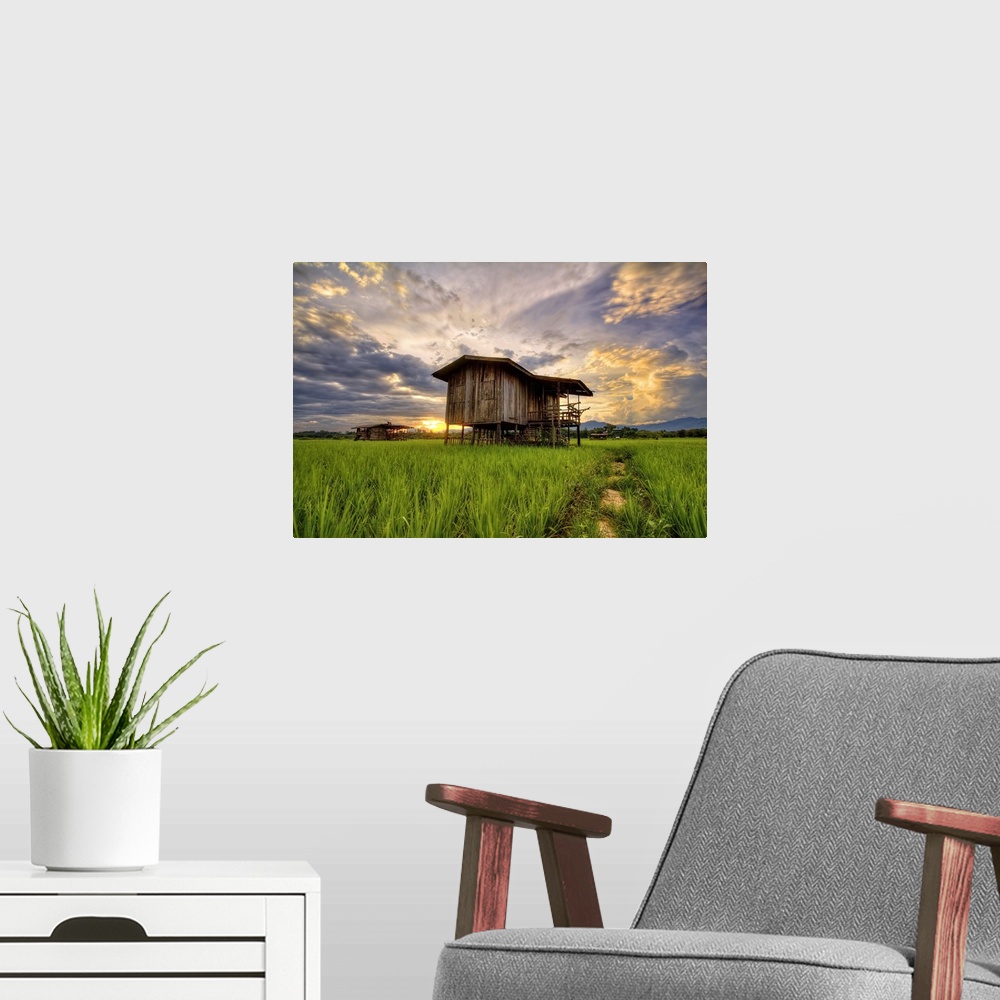 A modern room featuring An old wooden building in a field under a colorful sunset sky.