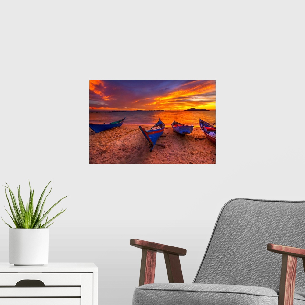 A modern room featuring A row of small blue boats resting on the sandy beach with a brilliant sunrise.