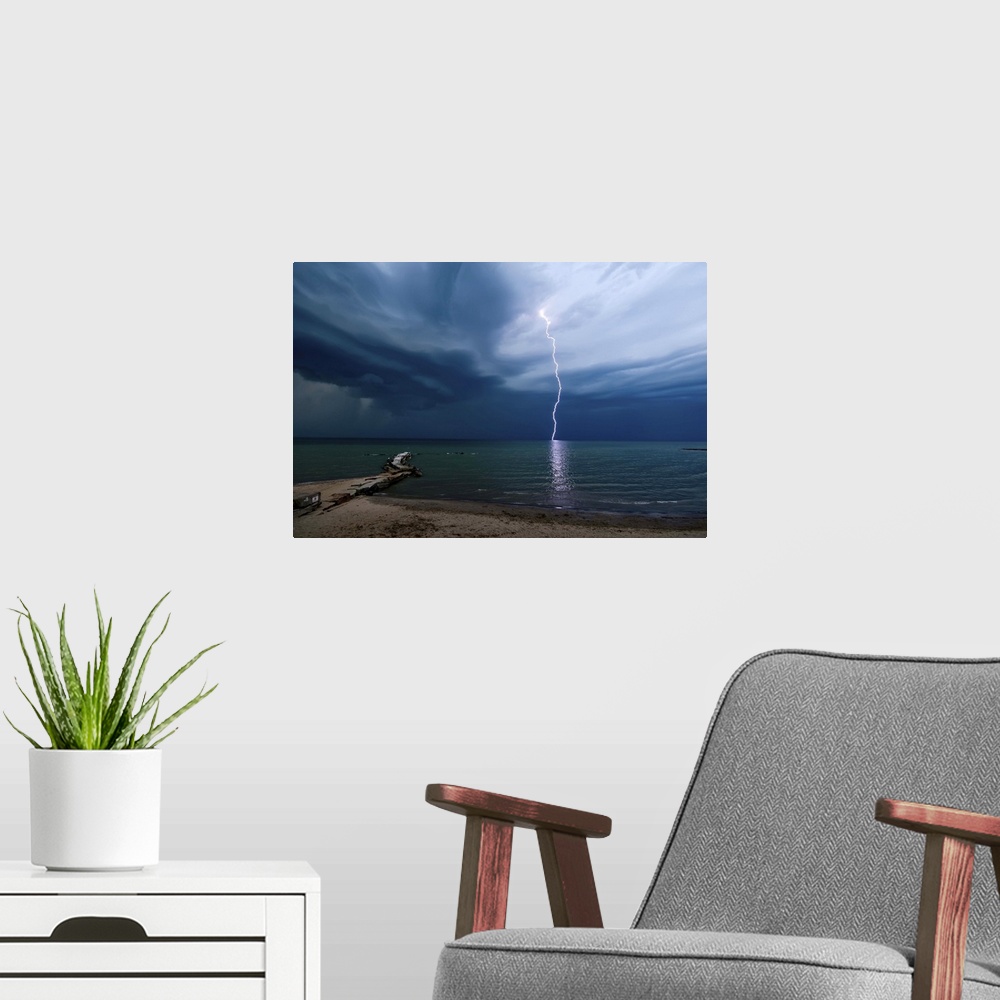 A modern room featuring Photograph of a lightning strike over water.
