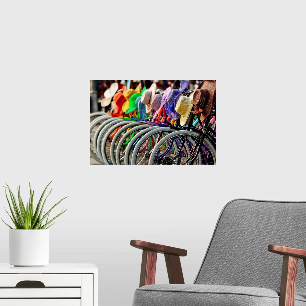 A modern room featuring A row of bicycles with rainbow hats hanging on the handlebars.