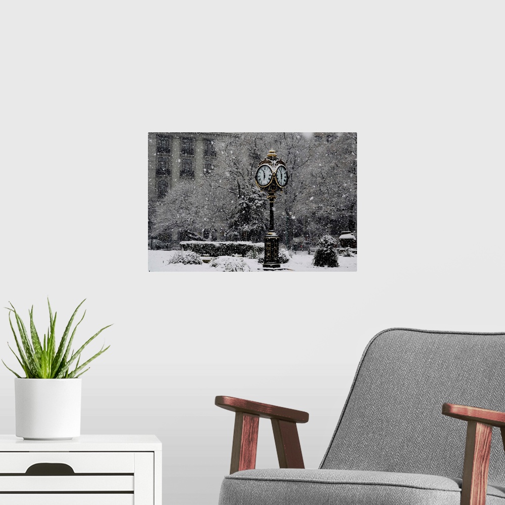 A modern room featuring A large clock standing in a park while snow falls around it.