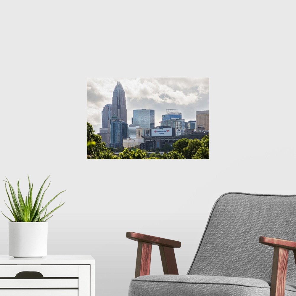 A modern room featuring A forest of trees in the foreground of the Charlotte North Carolina city skyline