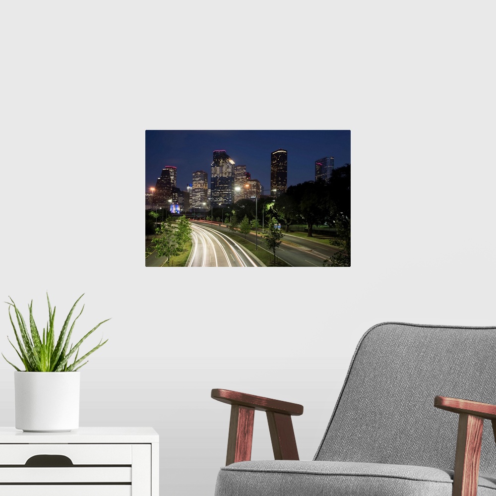 A modern room featuring Long exposure photograph of the Houston TX skyline at night from the highway with red and white l...