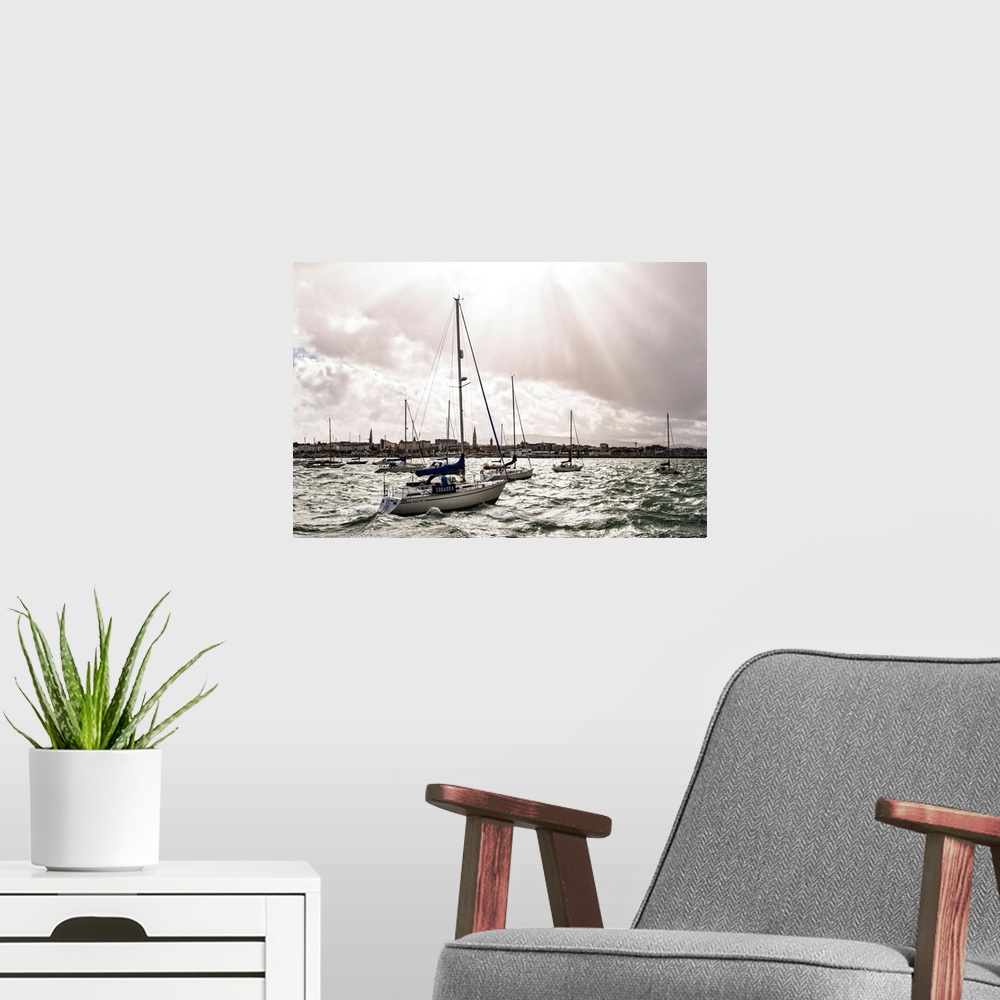 A modern room featuring Photograph of the sun peaking through the clouds over the River Liffey in Ireland, and sailboats ...