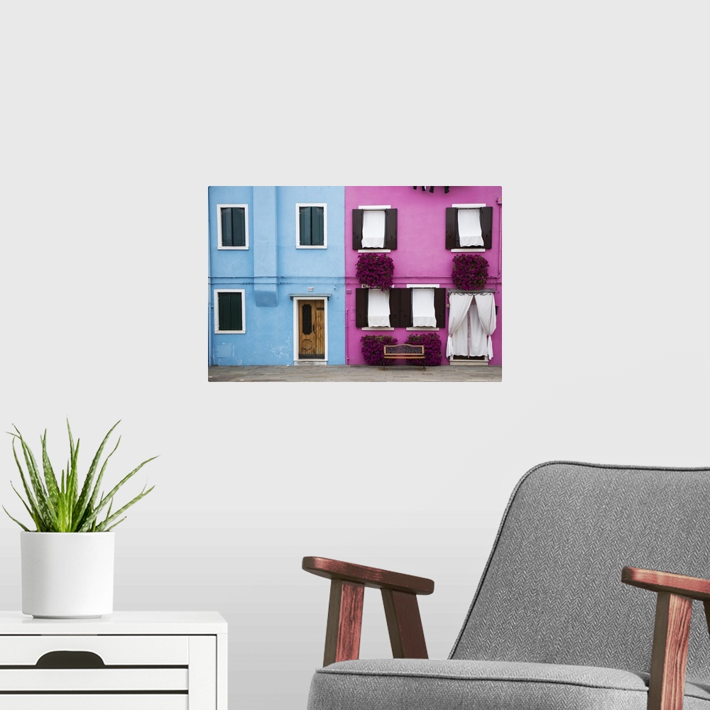 A modern room featuring Photograph of a colorful Venice Facade with a wooden door, windows, and magenta potted flowers on...