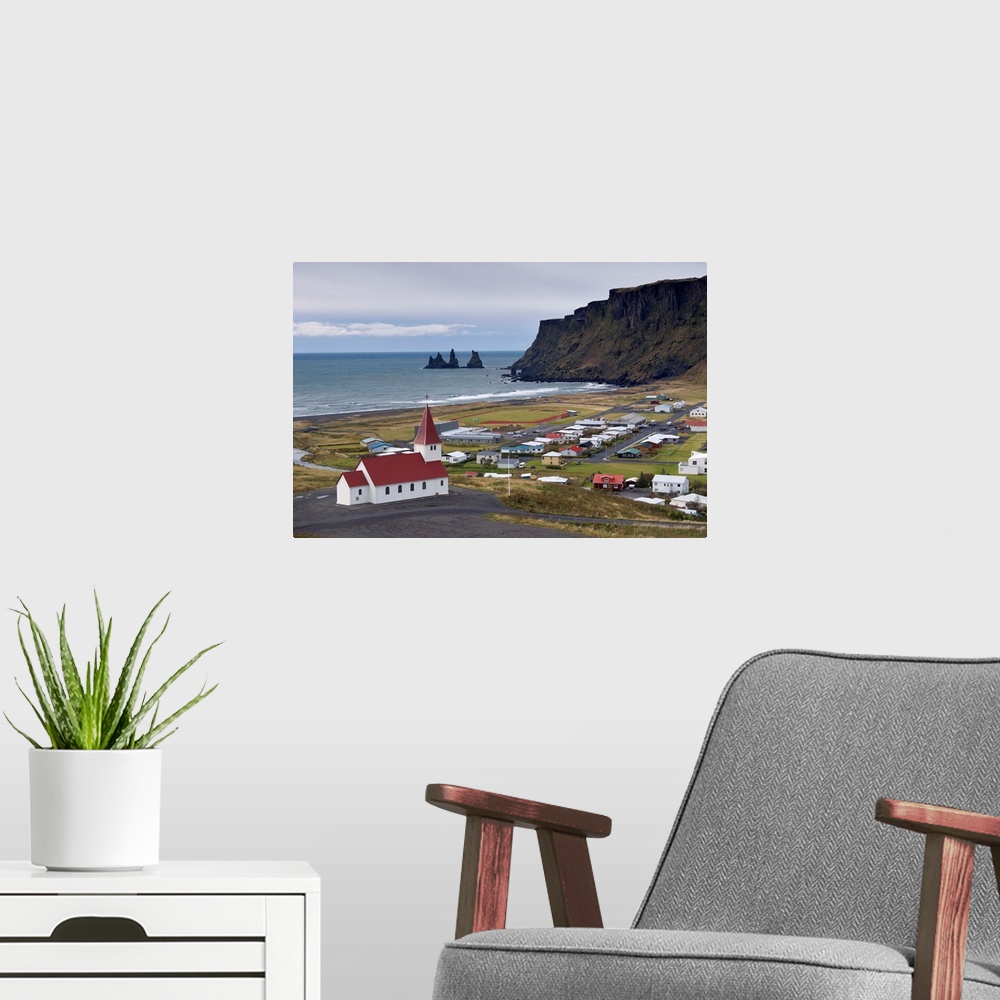 A modern room featuring Church, village of Vik and Reynisdrangar sea stacks in the distance, Iceland